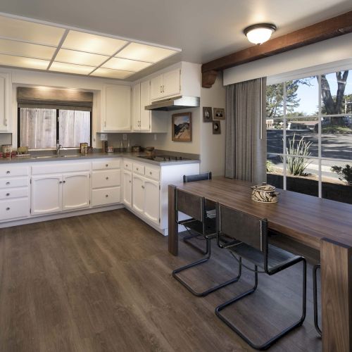 Cozy kitchen with white cabinets, a wooden dining table, and a large windowed door area; open layout, warm lighting, and a modern rustic vibe.